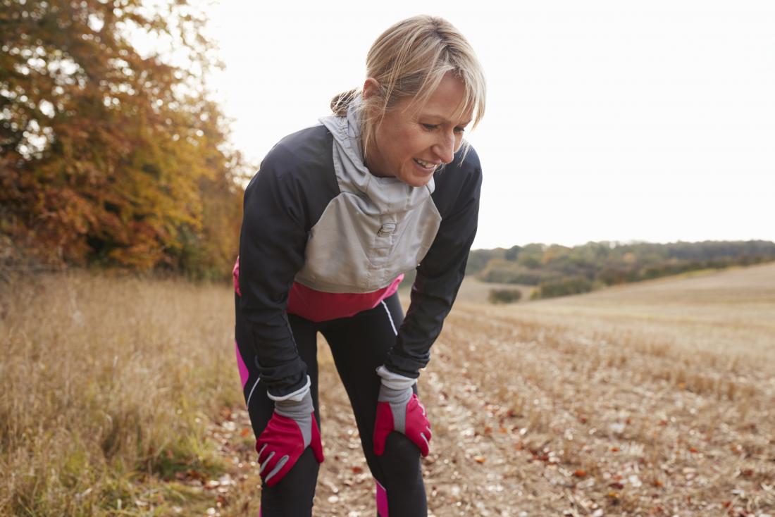 Woman outdoors out of breath in running gear experiencing exercise induced asthma.