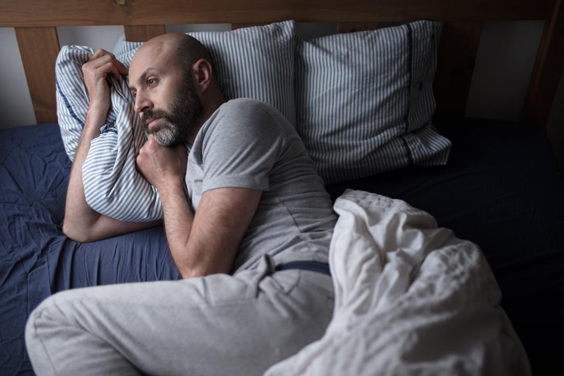 man with insomnia lying in bed