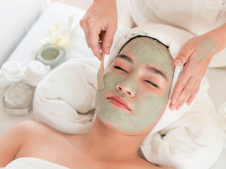 Face peeling mask, spa beauty treatment, skincare. Woman getting facial care by beautician at spa salon, side view, close-up