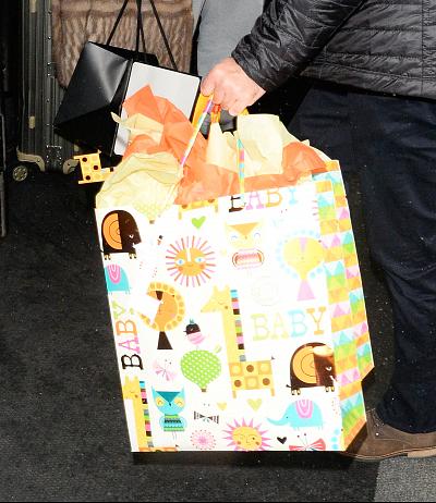 A member of Amal Clooney\'s entourage carried a bag full of baby gifts.