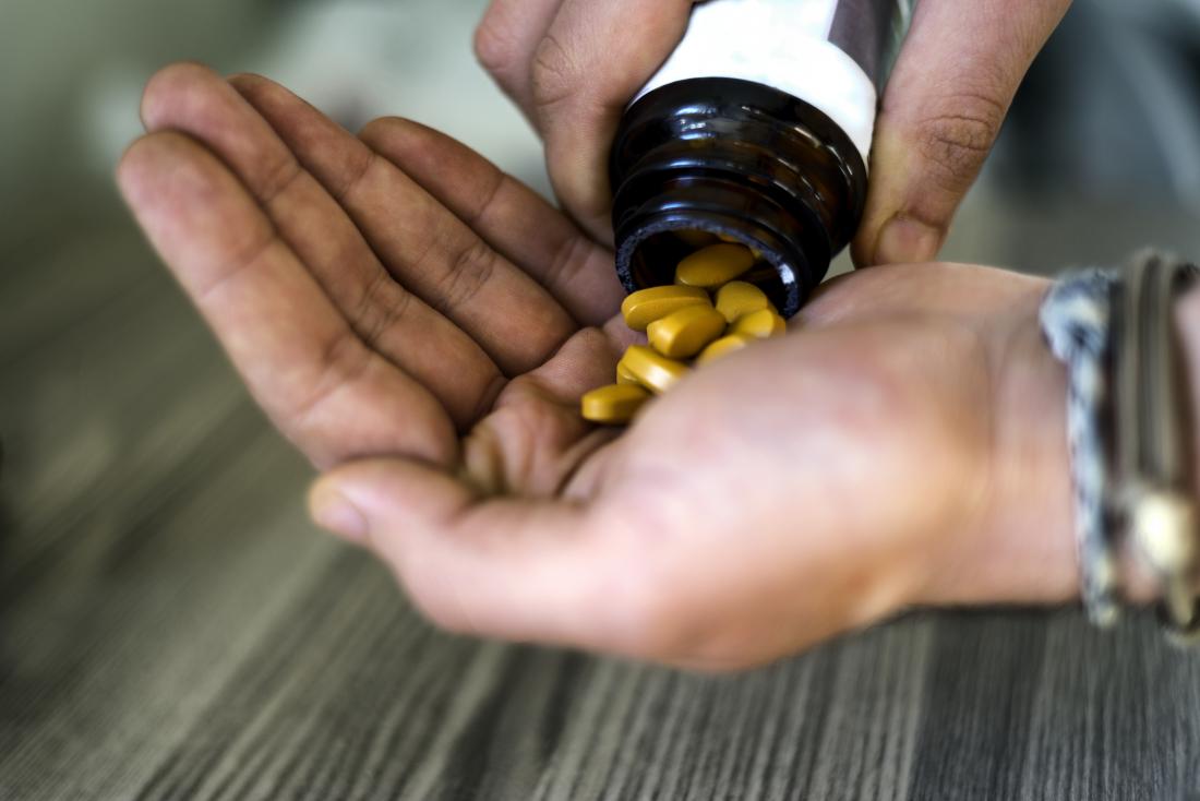 Person pouring B vitamin nutritio<em></em>nal supplements from bottle into palm