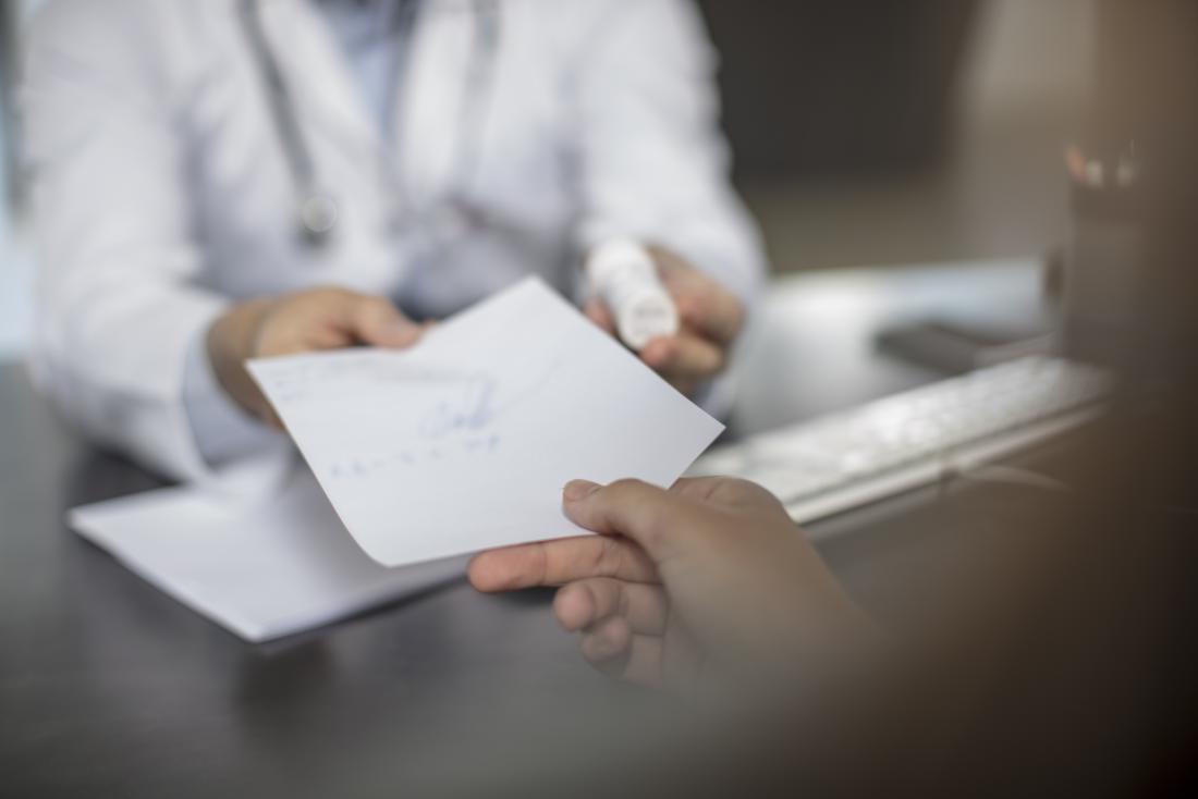 Doctor handing written pres<em></em>cription to patient
