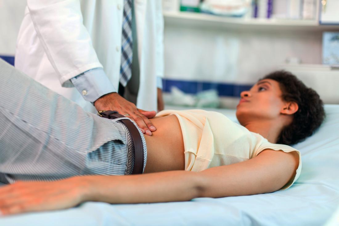 a woman getting her abdomen examined by a doctor. 