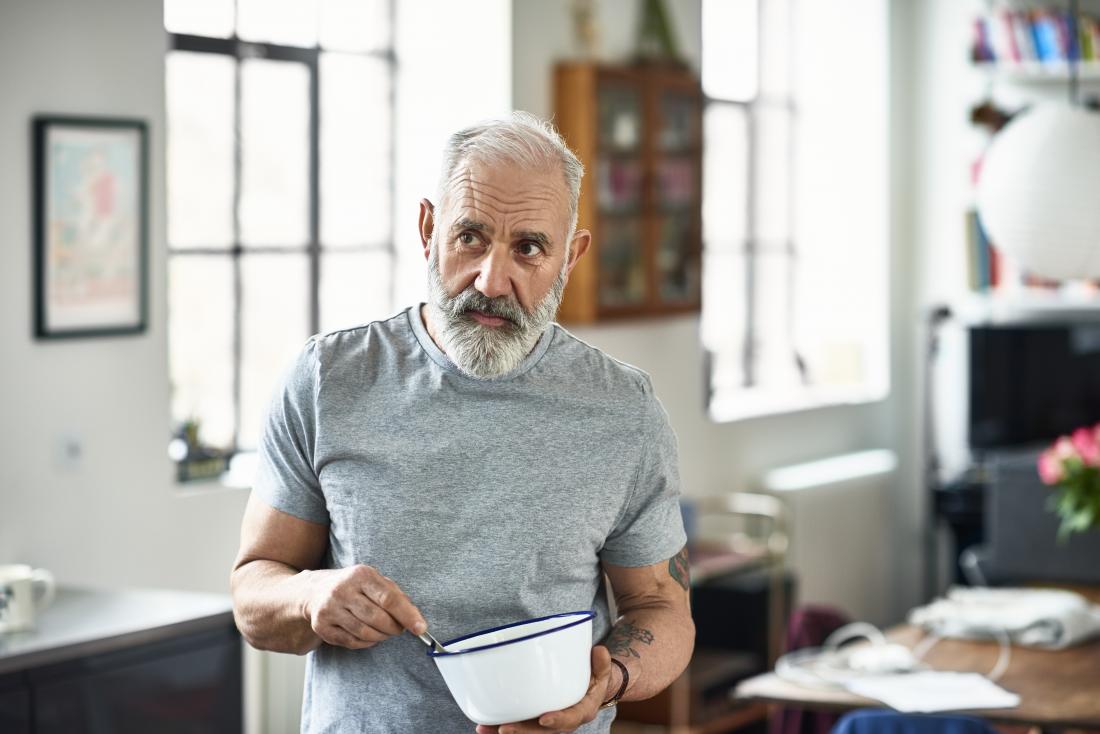Mature or senior man in house mixing food in bowl