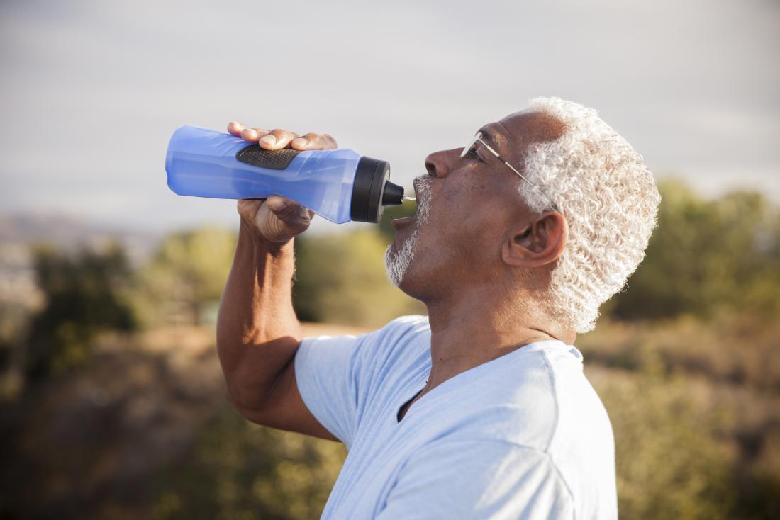 a man drinking water whilst outside on a sunny day
