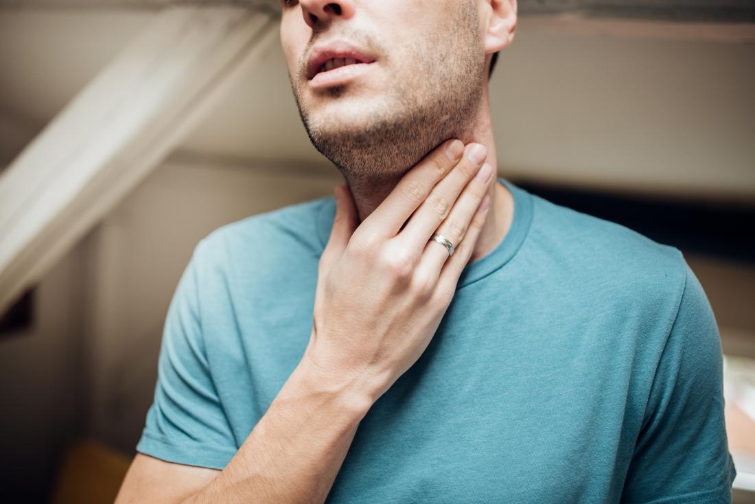 man holding his throat due to a sore throat