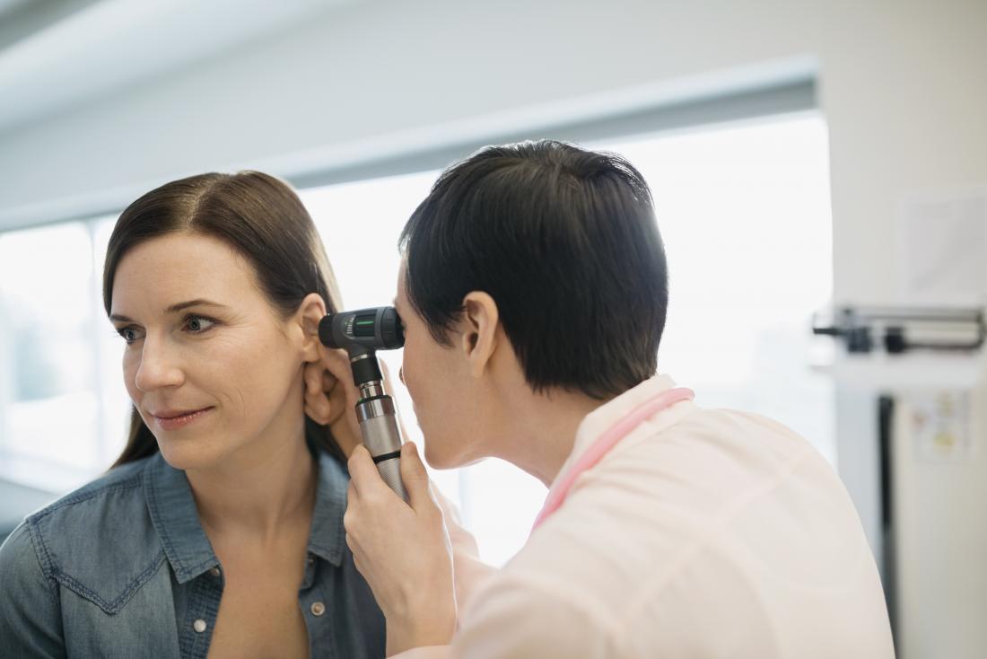 woman havin<em></em>g ear examined by doctor with otoscope