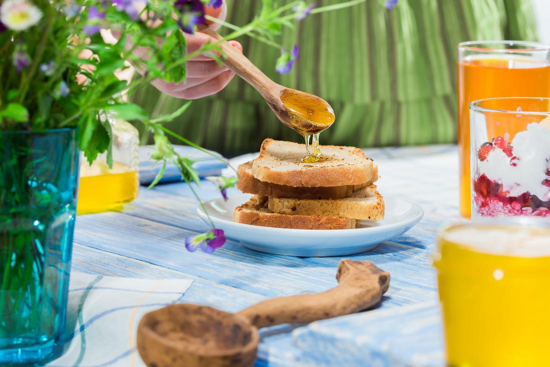 woman pouring ho<em></em>ney on to toast